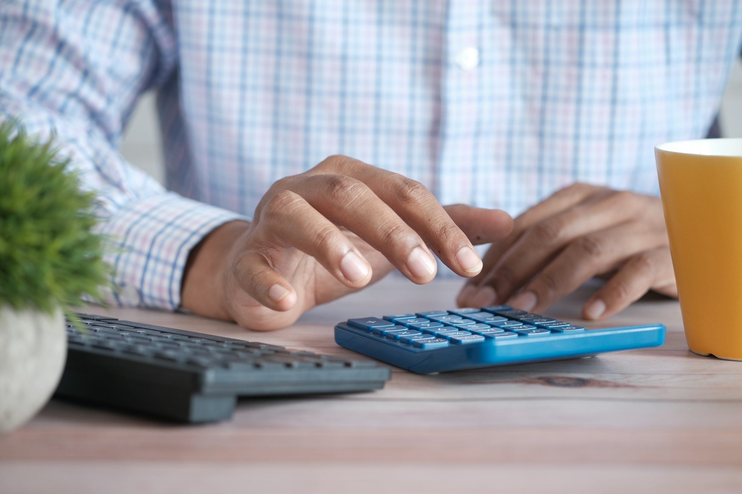 Accountant working a bright blue calculator at a desk